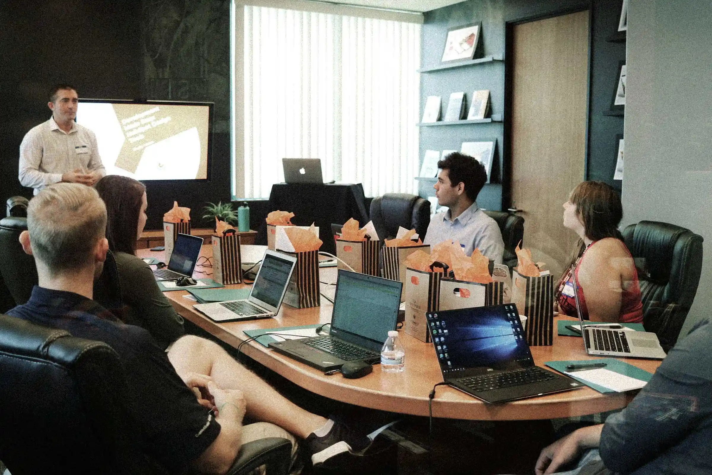 Presentation with people gathered around a table with laptops
